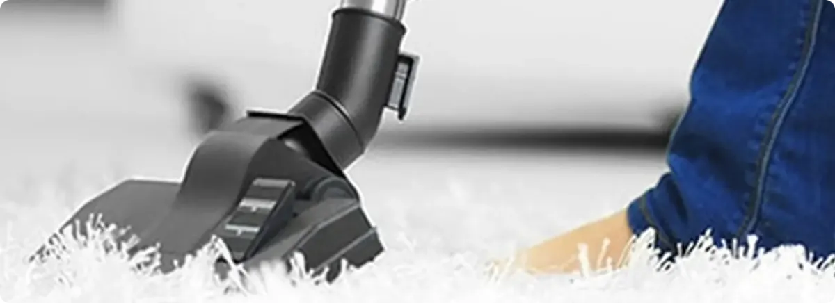 Close-up of a professional vacuuming a white carpet in Grand Island.